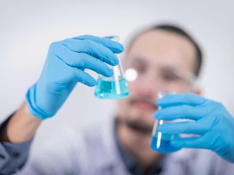 man looking at two chemicals in lab