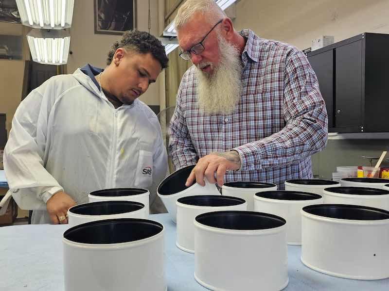 Chuck Zinke inspects parts with a team member at their facility in Arizona.