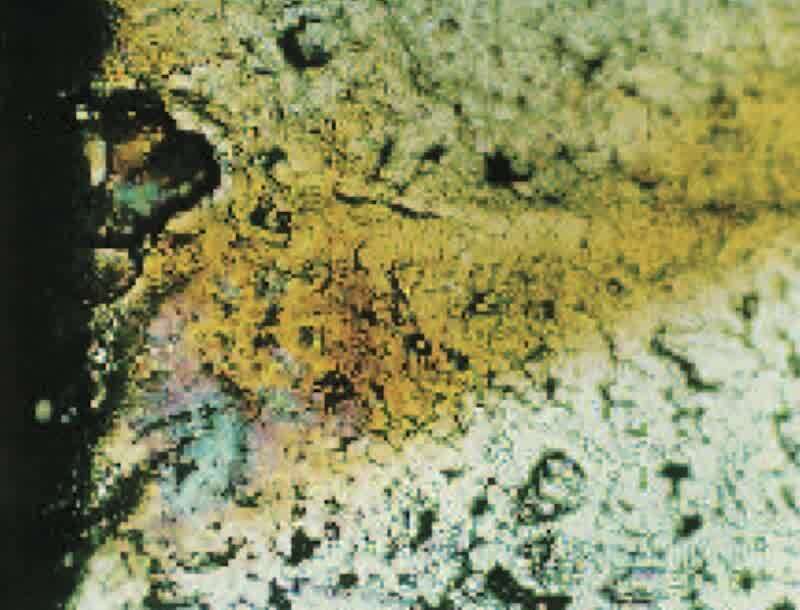 100X surface photo of stain on electroless&nbsp;nickel-plated part, showing the presence of large surface pores on the left edge that may be the source of stain following corrosion-resistance testing.
