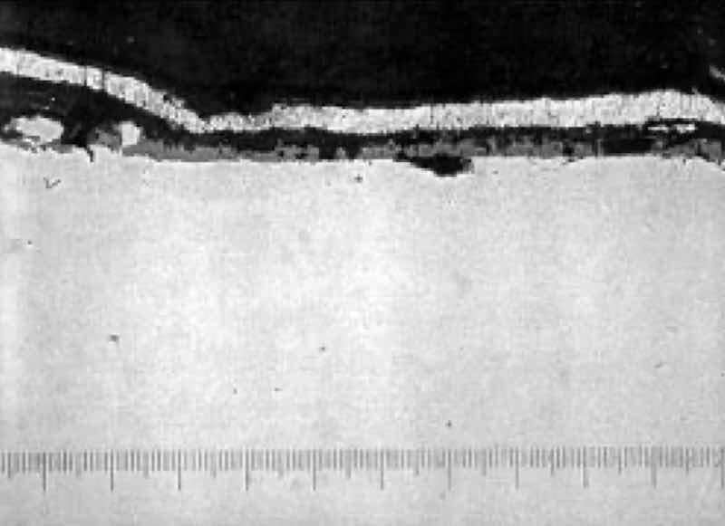 Photomicrograph at 600X, of heat treat scale on zinc plated steel parts, evidencing poor adhesion.