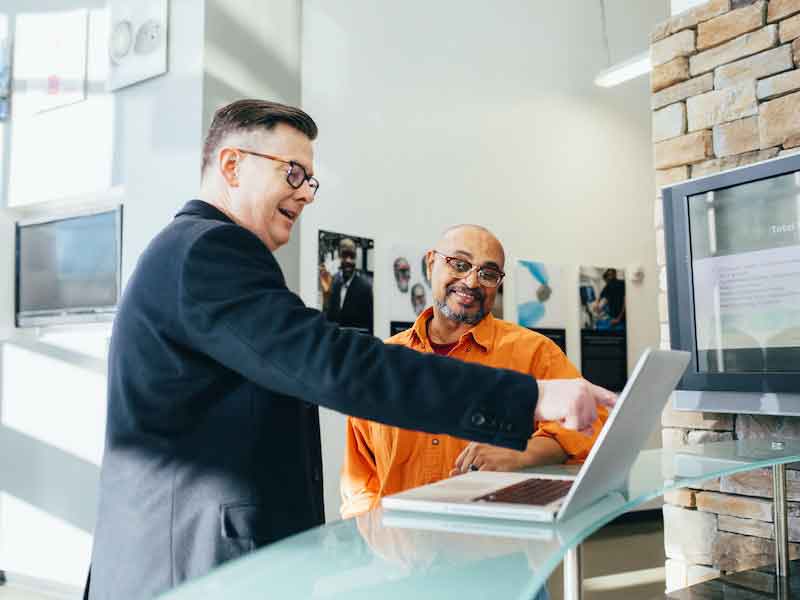 two men talking at a computer