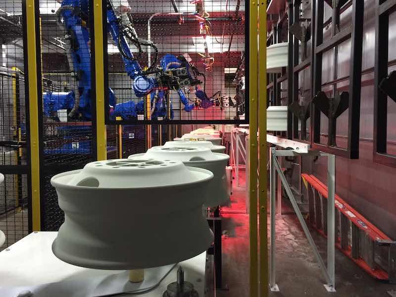 Robotic unloading  of wheels on a powder coating system.