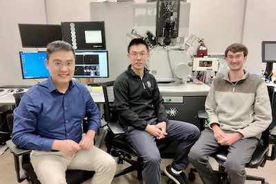 Co-lead authors of the new study, from left, Xin Yu, Teng Cui, and Geoff McConohy. The equipment behind them is the focused ion beam/scanning electron microscope system that they used for this research. (Image credit: Xin Xu)