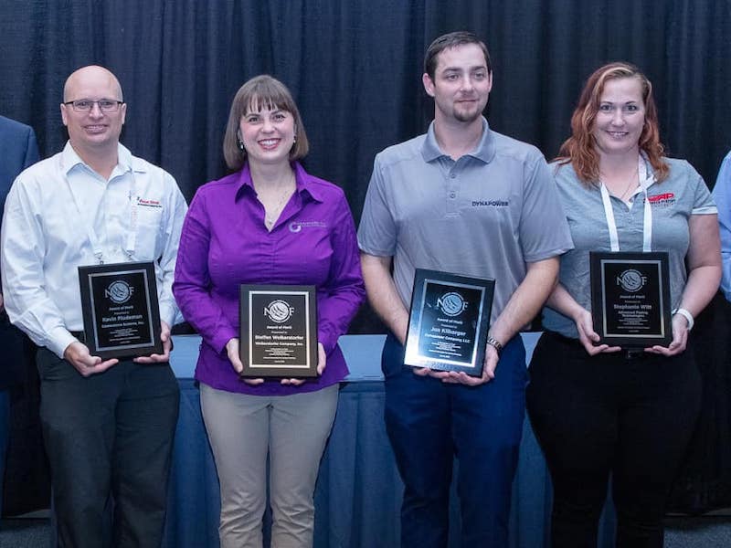 four people holding awards