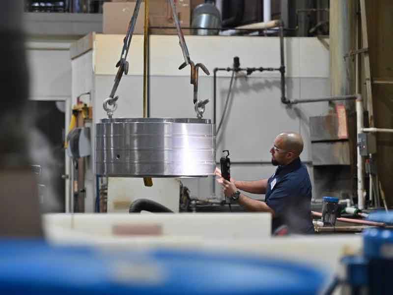 man putting part in plating bath