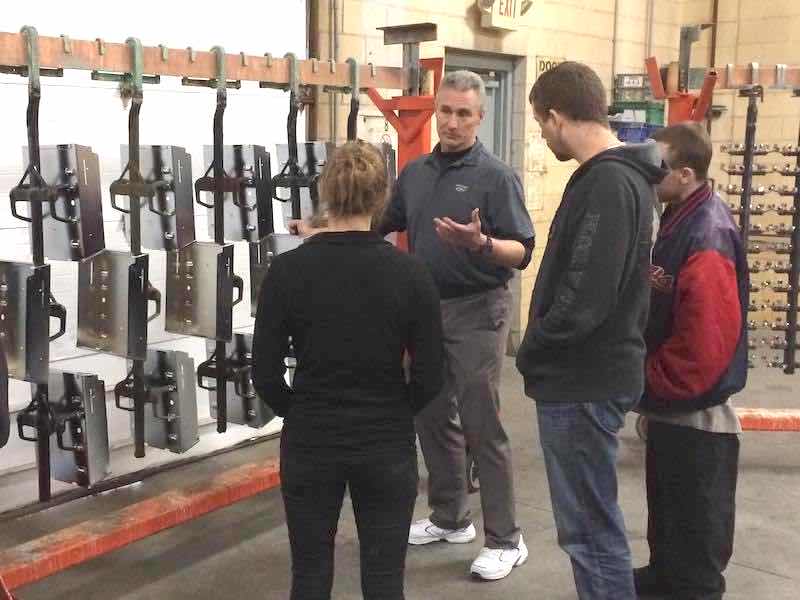 people listening to a person speak at a plating rack